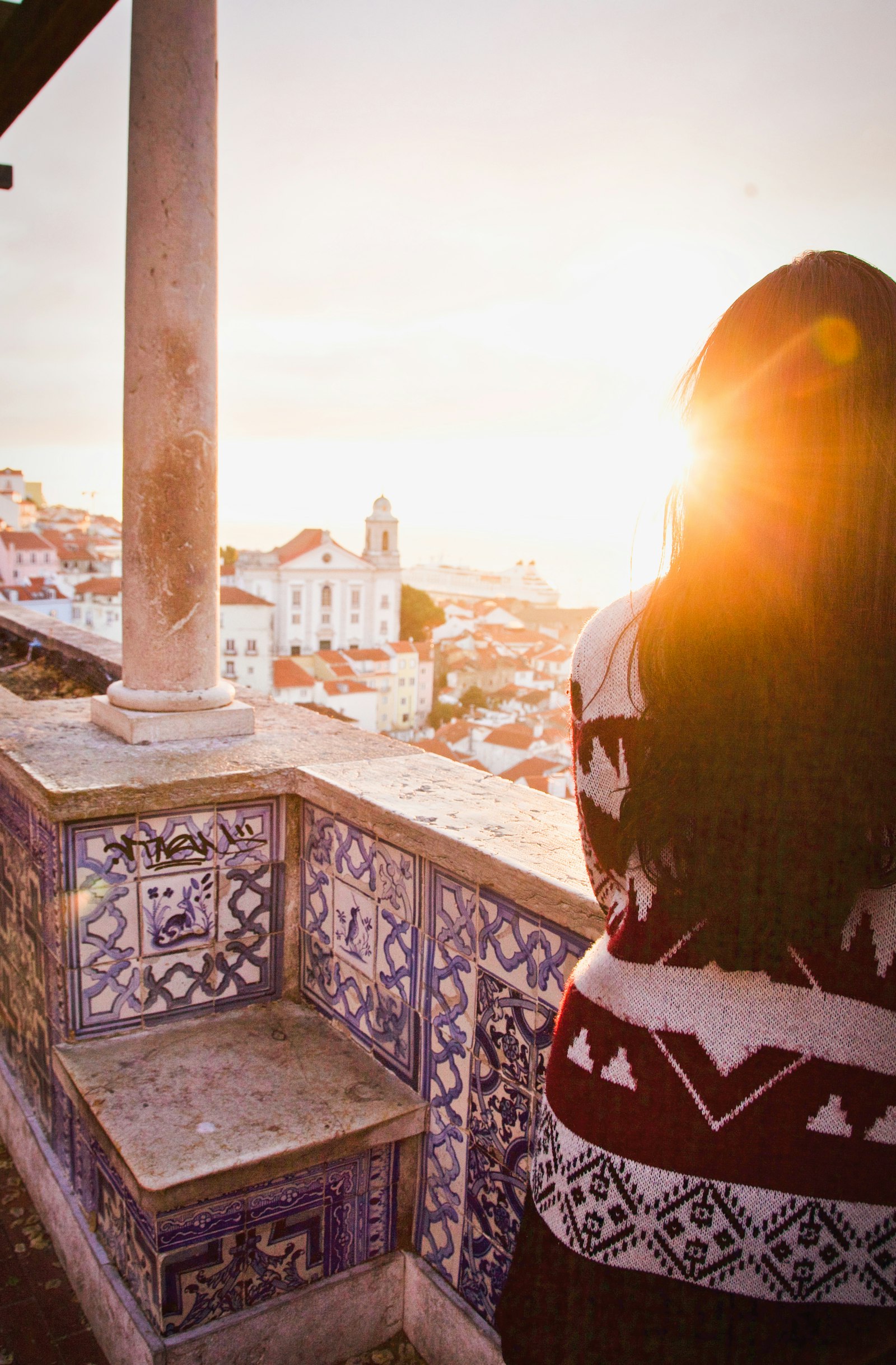 A traveller looking out over a sunlit coastal town at golden hour